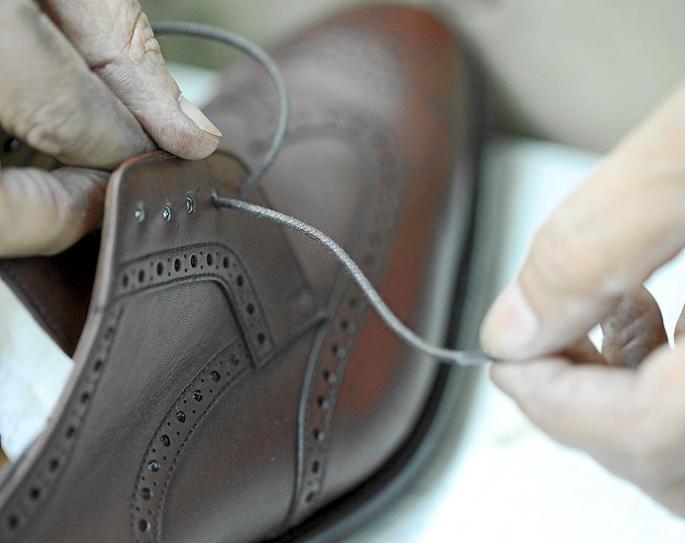 Am Ende der Fertigung zieht der Schuhmacher den Schnürsenkel in sein Handwerk ein.