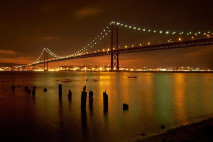 Die Brücke des 25. April überspannt den Tejo in Lissabon – hier beleuchtet bei Nacht.